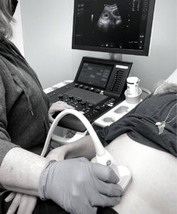technician performing ultasound scan over abdomen